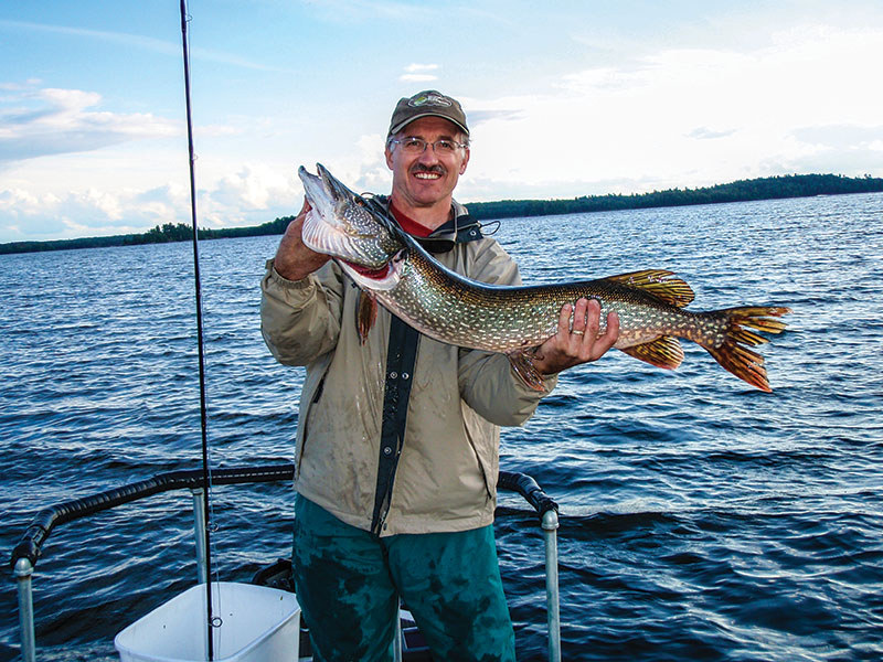 man in boat holding pike